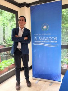 Enner Morales standing next to a sign in Spanish which says "El Salvador, unanomonos para crecer"