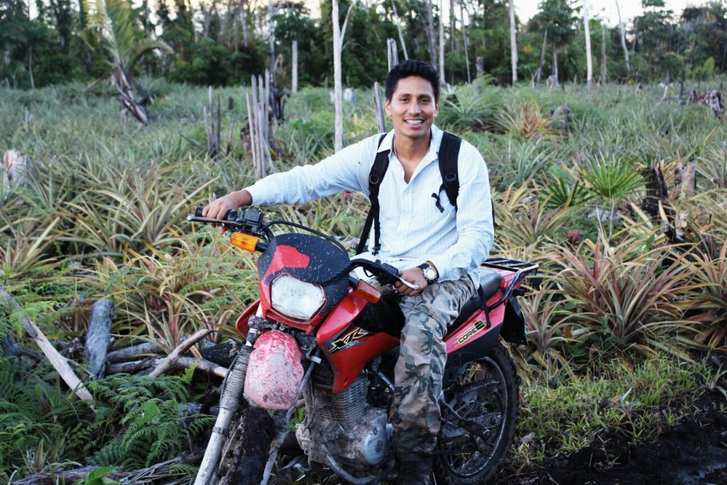 Marco riding a red dirt bike in a jungle in Peru.