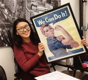Meerim holding a Rosie the Riveter photo containing the words "We Can Do It!".