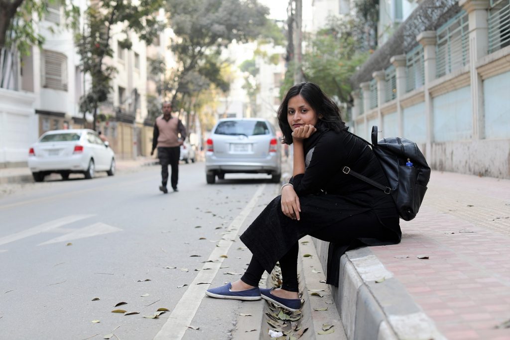 The portrait that Brandon took of Nalifa. Nalifa sits on the sidewalk with her feet in the gutter on a quiet street in Dhaka