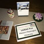 Vicky's UGRAD Post on a table with a succulent, calendar, and notebook