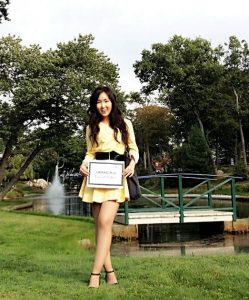 Chessy stands with her UGRAD post in front of a bridge and fountain on campus