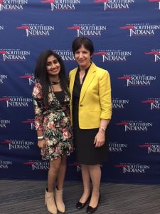 Utthara is pictured with the Vice Provost of USI, Heidi Gahan, in front of a USI banner.