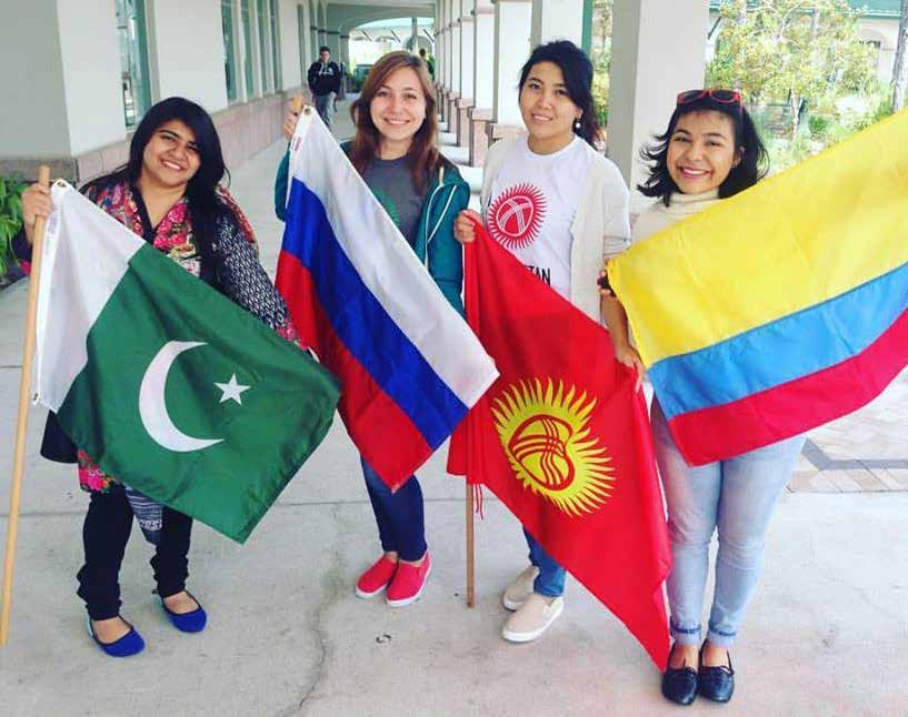 Four people stand holding the flags from their home countries.
