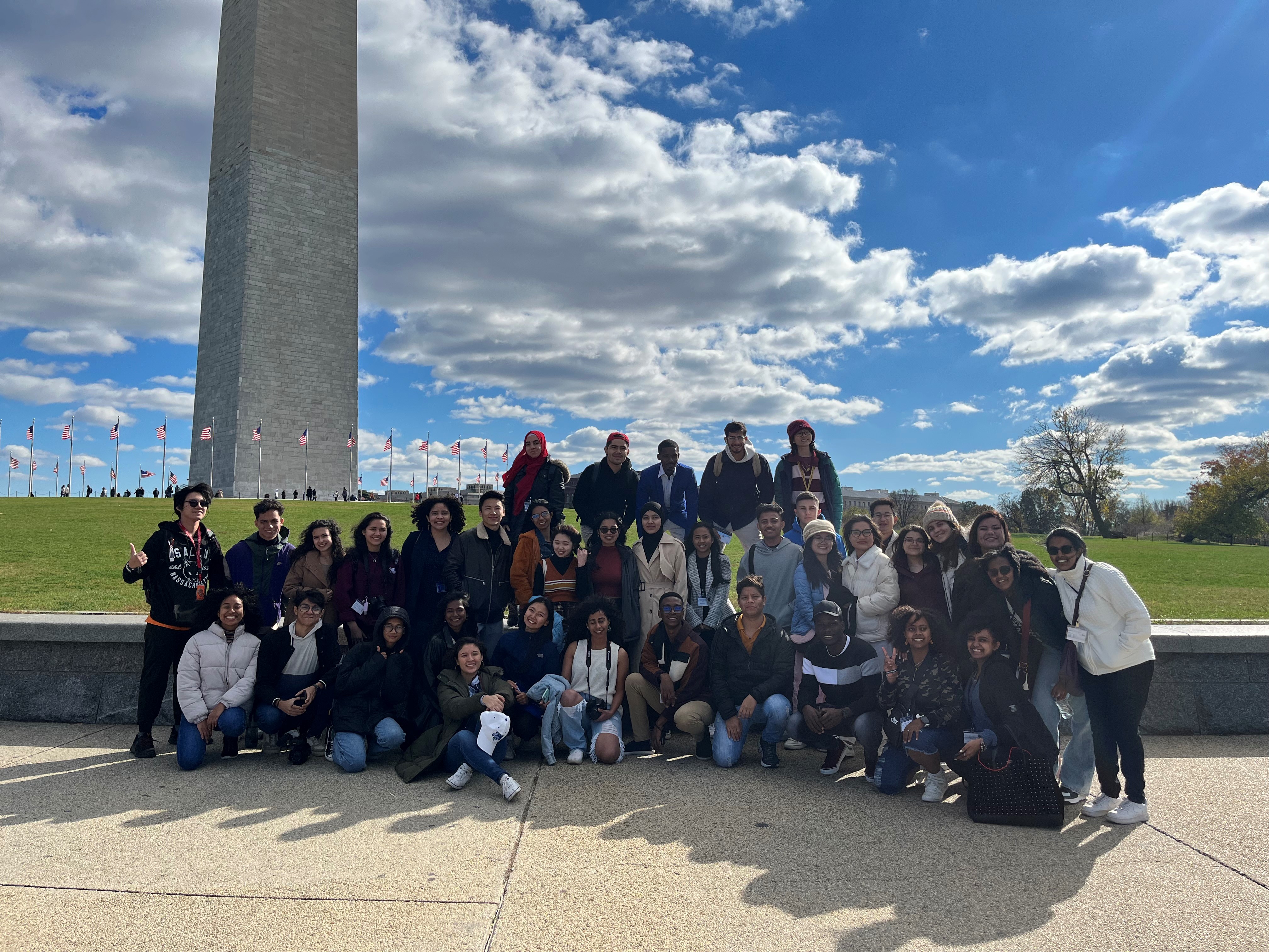 Group of about 30 students stand together in front of the Washington Monument
