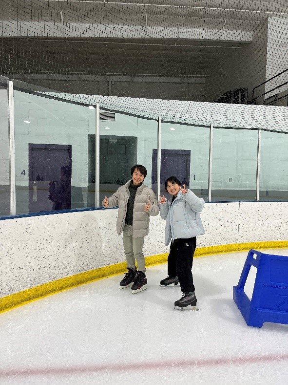 Two students stand smiling on an ice skating rink